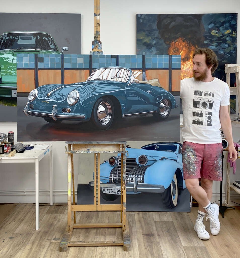 Manu Campa in his atelier, posing with a Porsche 356 painting