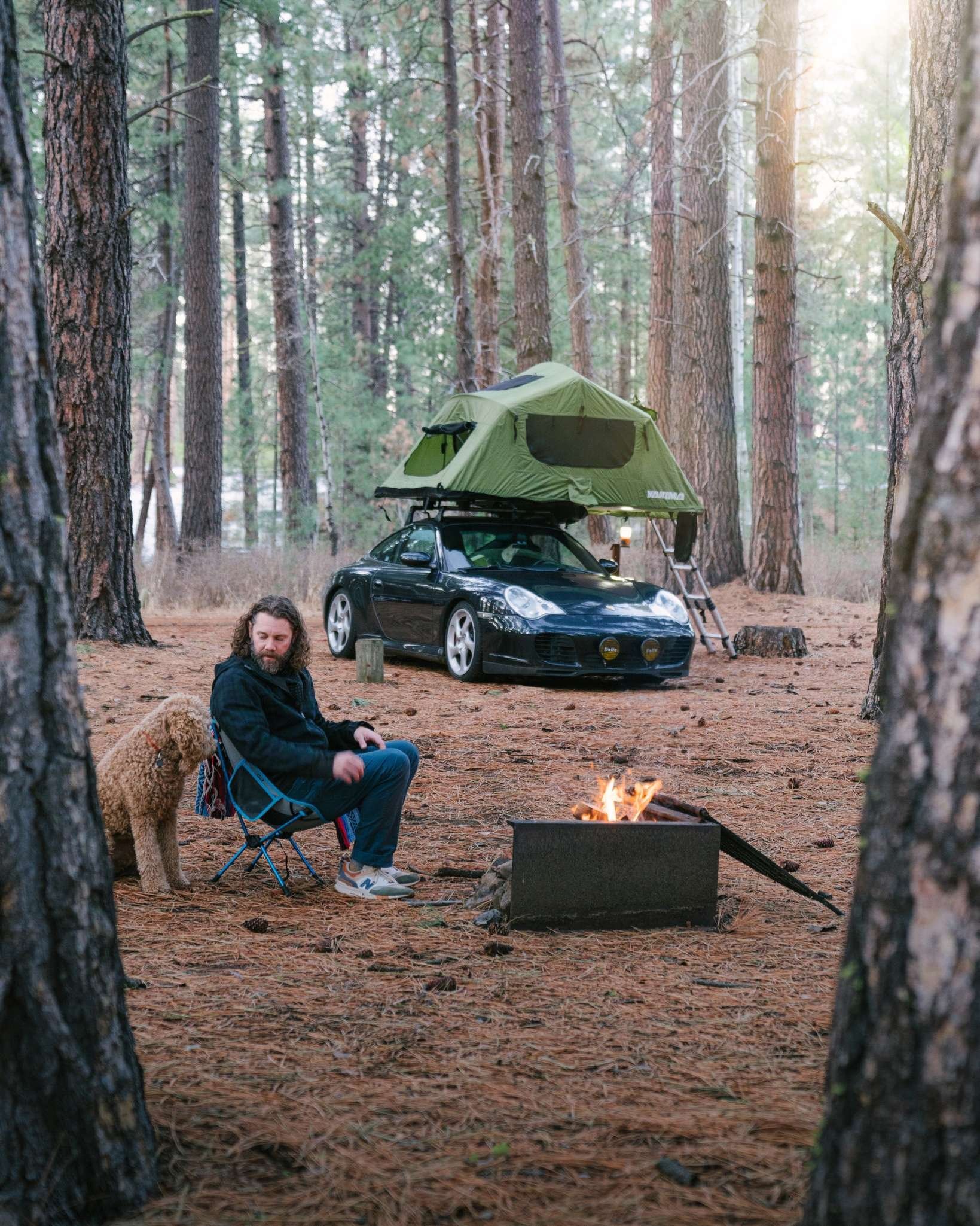 996roadtrip Porsche 996 Carrera 4S Brock Keen sitting in the forest with his dog Lucy next to a bonfire