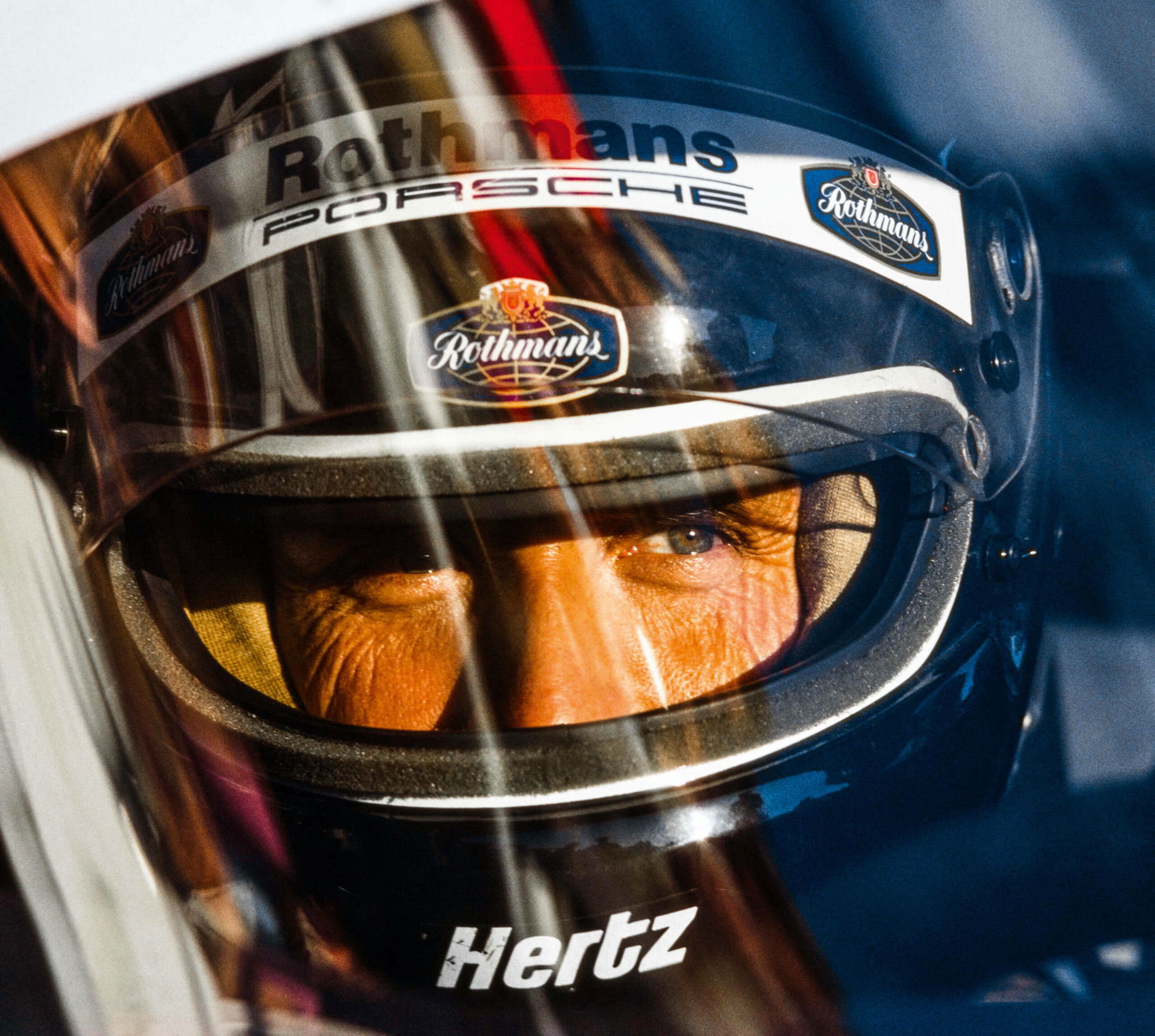 Jacky Ickx portrait with Rothmans Porsche helmet at the 24h of Le Mans 1985 - Porsche Racing Moments Rainer Schlegelmilch