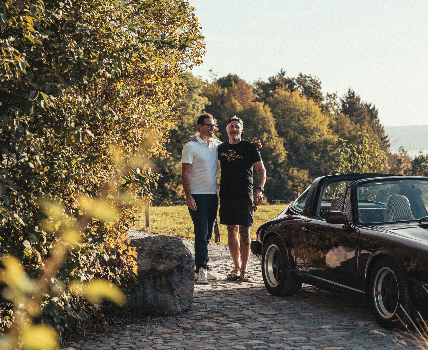 Dr. Manuel Köhne und Tibor Simai neben Porsche 911 SC in Rubinrot