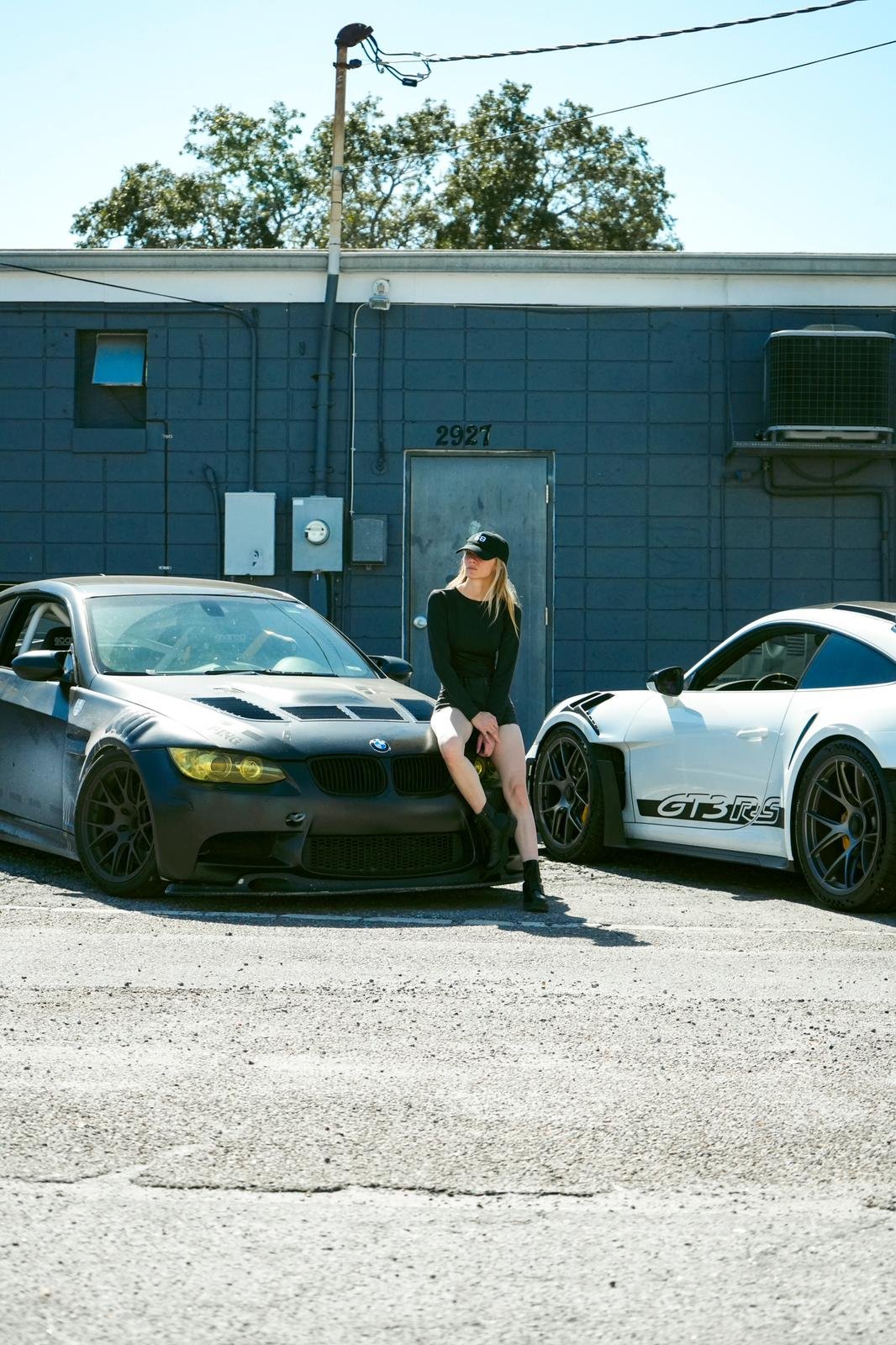 Rae Roberts sitting on her BMW M3 E92 next to a Porsche 992 GT3 RS