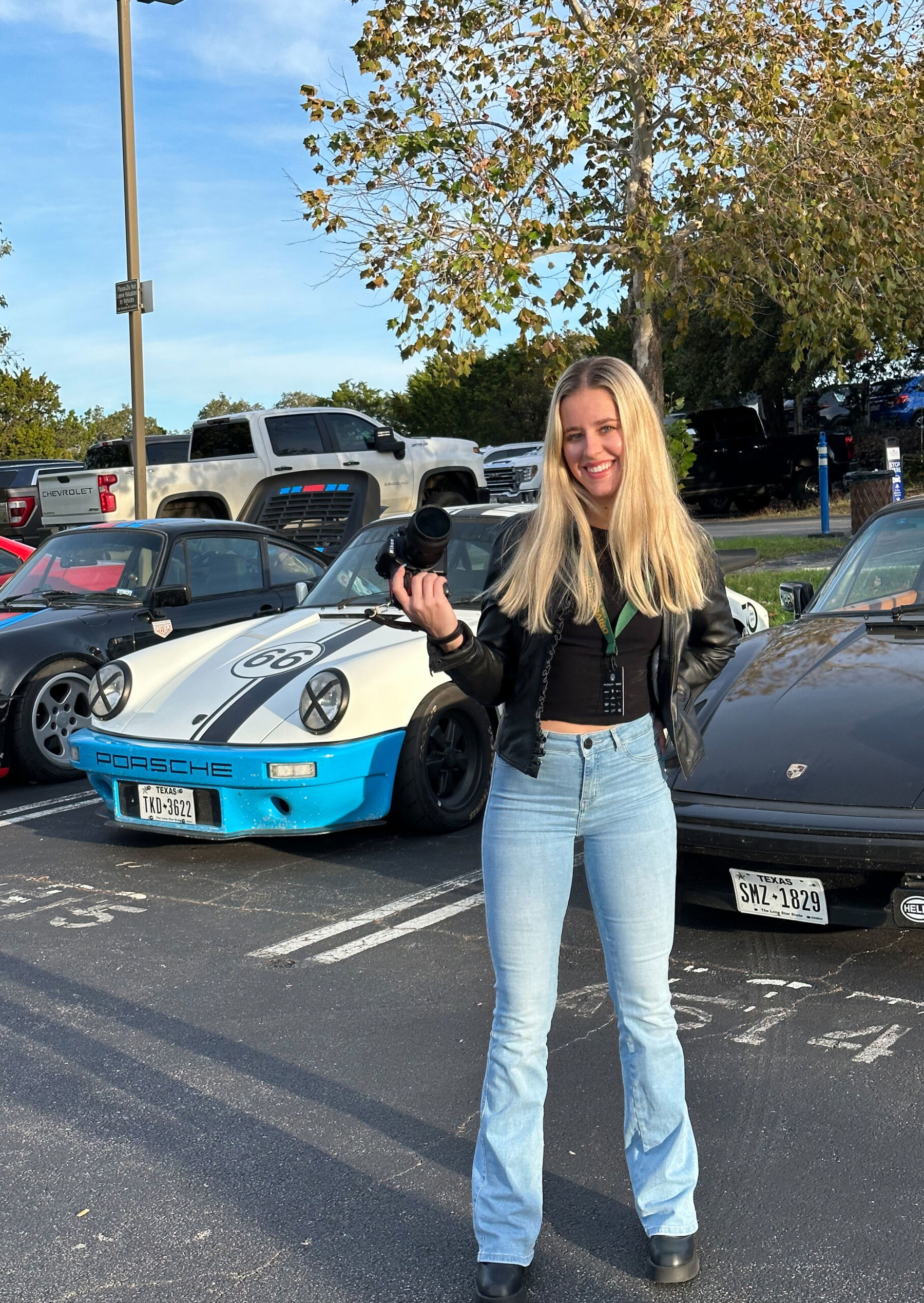 Kaitlyn Clink in front of Porsches in a parking lot
